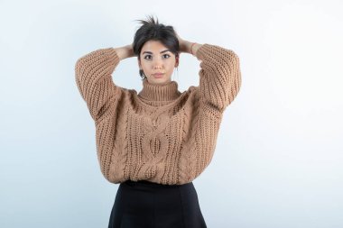 Örgü kazaklı güzel bir kadının beyaz arka planda saçını tutarken çekilmiş fotoğrafı. Yüksek kalite fotoğraf