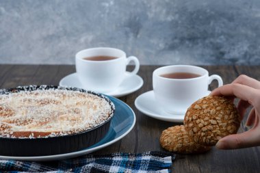 Tahta bir masaya yerleştirilmiş tahıllı ve tohumlu yulaf ezmeli kurabiye yiyen bir kadın. Yüksek kalite fotoğraf