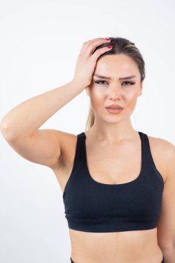 Siyah spor elbiseli sarışın kadın beyaz bir duvarın üzerinde dikilip poz veriyor. Yüksek kalite fotoğraf