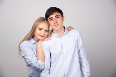 Gri duvarda birbirine sarılan genç bir çiftin portresi. Yüksek kalite fotoğraf