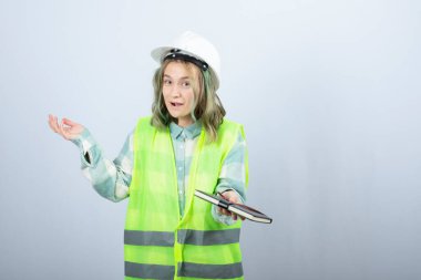 Genç bayan mühendisin beyaz duvardan defter dağıtırken çekilmiş bir fotoğrafı. Yüksek kalite fotoğraf