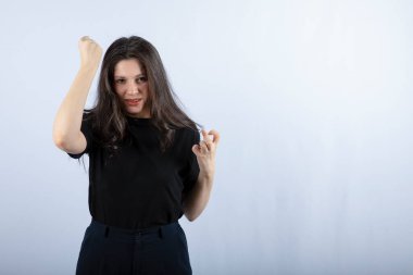 Beyaz arka planda kızgın bir ifadeyle duran esmer bir kızın fotoğrafı. Yüksek kalite fotoğraf