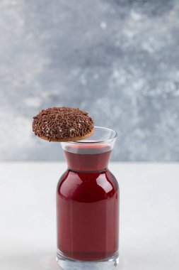Cookie with chocolate sprinkles placed on glass pitcher of wine . High quality photo
