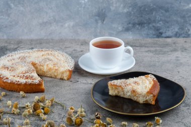 Lezzetli bir parça kek ve beyaz bir fincan sıcak çay ile siyah bir tabak. Yüksek kalite fotoğraf
