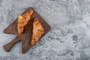 Tahta bir kesme tahtasına taze ve lezzetli kruvasanlar konmuş. Yüksek kalite fotoğraf