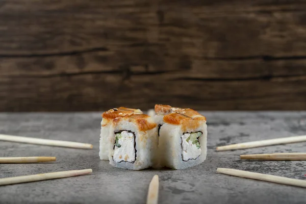 Unagi sushi Philadelphia rolls with wooden disposable chopsticks placed on a stone background . High quality photo