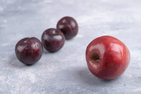 Frutas Ciruela Frescas Enteras Con Una Manzana Roja Sobre Fondo —  Fotos de Stock