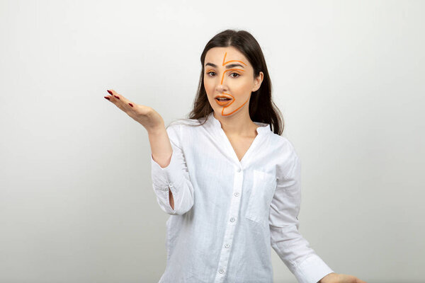 Image of young woman with painted face showing opened palm . High quality photo