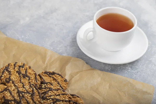 Çikolata kaplı yulaf ezmeli kurabiyeler ve bir fincan çay. Yüksek kalite fotoğraf