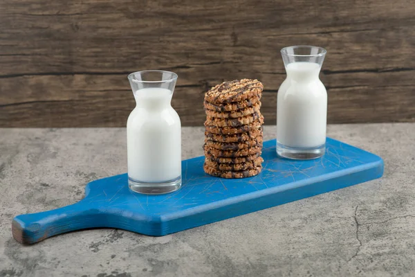 ブルーの板の上にオートミールクッキーとミルクの2つのガラスのジャグ 高品質の写真 — ストック写真