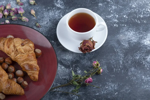 Fındıklı kruvasan tabağı ve mermer üzerine siyah çay. Yüksek kalite fotoğraf