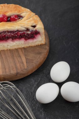 Dilimlenmiş lezzetli peynirli kek, böğürtlenli ve çiğ yumurta ve siyah arka planda. Yüksek kalite fotoğraf