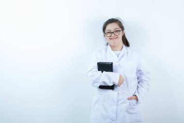 Doktor üniformalı genç bir kız ayakta ve elinde not defteri var. Yüksek kalite fotoğraf