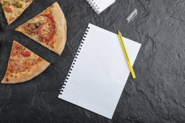 Baharatlı biberli pizza dilimleri ve siyah yüzey üzerine boş kağıt. Yüksek kalite fotoğraf