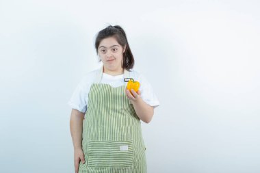 Kareli önlüğün içinde elinde sarı dolmalık biber tutan genç ve güzel bir kız. Yüksek kalite fotoğraf