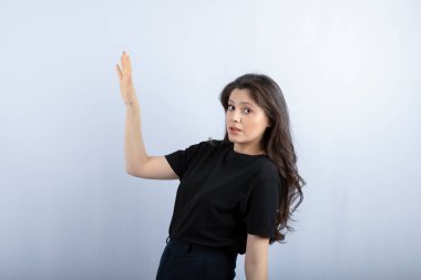 Uzun saçlı bir kızın beyaz arka planda birini araması. Yüksek kalite fotoğraf