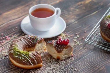 Çikolatalı çörekler, üzerine serpiştirilmiş şekerler ve tahta bir masaya konmuş bir fincan çay. Yüksek kalite fotoğraf