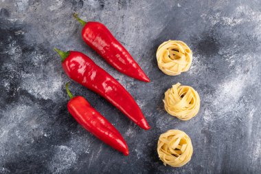Çiğ makarna yuvaları ve mermer yüzeyde kırmızı biber. Yüksek kalite fotoğraf