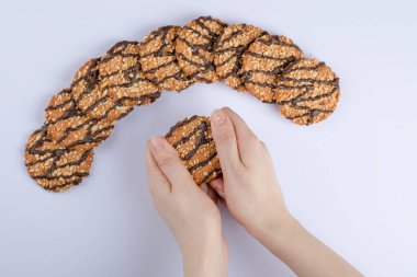 Beyaz arka planda çikolata şurubuyla yulaf ezmeli kurabiye kıran kadın elleri. Yüksek kalite fotoğraf