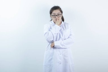 Doktor üniformalı genç bayan ayakta ve sessiz işareti yapıyor. Yüksek kalite fotoğraf