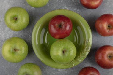 Yeşil kase mermer yüzeyde kırmızı ve yeşil elmalar. Yüksek kalite fotoğraf