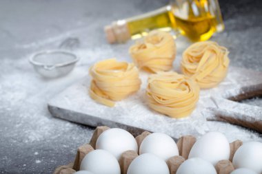 Çiğ tagliatelle, siyah yüzeyde un, yağ ve çiğ yumurta ile yuva yapar. Yüksek kalite fotoğraf