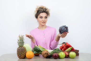 Masada elinde mor lahanayla oturan genç ve güzel bir ev hanımı. Yüksek kalite fotoğraf