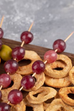 Kurutulmuş elma halkaları, kırmızı üzümler ve ahşap tabakta kumkatlar. Yüksek kalite fotoğraf