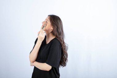 Beyaz arka planda fırçayla gölge uygulayan genç ve güzel bir model resmi. Yüksek kalite fotoğraf