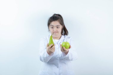 Doktor üniformalı genç bir kız elinde yeşil elmalı armut meyvesi tutuyor. Yüksek kalite fotoğraf