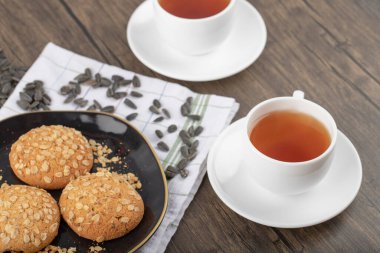 Tahta bir masaya yerleştirilmiş beyaz fincanlı çok tahıllı kurabiyeler. Yüksek kalite fotoğraf