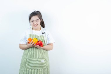 Kareli önlüğün içinde elinde sebzelerle duran genç ve güzel bir kız. Yüksek kalite fotoğraf