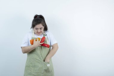 Kareli önlüğün içinde duran ve cebine sebze koyan genç ve güzel bir kız. Yüksek kalite fotoğraf