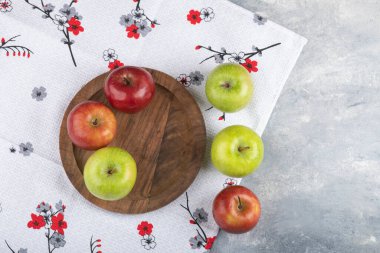 Masa örtüsündeki ahşap bir tabakta izole edilmiş yeşil ve kırmızı olgun elmalar. Yüksek kalite fotoğraf