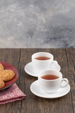 Kırmızı tabak ve yulaflı kurabiyeler ahşap masada bir fincan çay. Yüksek kalite fotoğraf