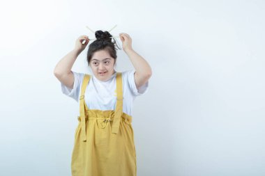 Beyaz duvara karşı duran ve poz veren genç, güzel bir kız. Yüksek kalite fotoğraf