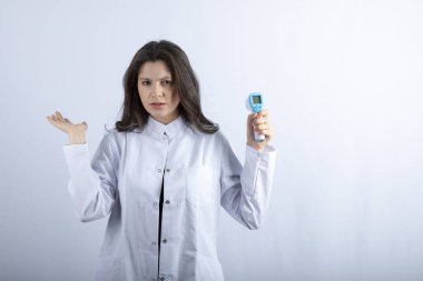 Beyaz arka planda termometreyi tutan genç doktorun fotoğrafı. Yüksek kalite fotoğraf