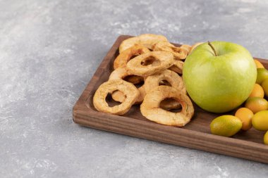 Taze kumkat ahşap tabağı, mermer zemin üzerinde elma ve kurutulmuş elma halkaları. Yüksek kalite fotoğraf