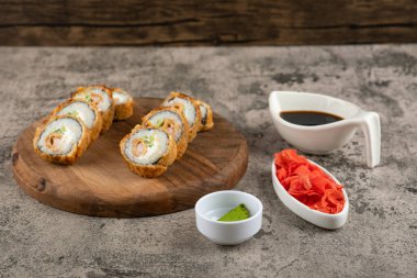 Kaya yüzeyinde somon ve sosla kızartılmış tahta suşi ruloları. Yüksek kalite fotoğraf