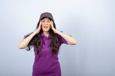 Mor üniformalı teslimatçı kızın portresi ayakta ve başı ağrıyor. Yüksek kalite fotoğraf