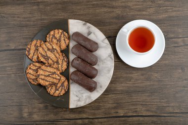 Çekirdekli kurabiyeler ve mermer tabakta bir fincan çayla çikolatalı kek. Yüksek kalite fotoğraf