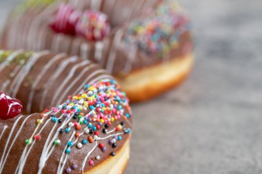 Çikolata kaplı donutlar, taştan arka planda serpiştirilmiş meyve parçaları ile süslenmiş. Yüksek kalite fotoğraf