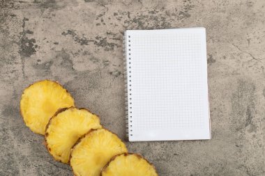 Taş zeminde sulu olgun ananas dilimleri ve defter. Yüksek kalite fotoğraf