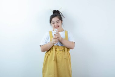 Genç ve güzel kız model ayakta ve beyaz duvara karşı cam şişe tutuyor. Yüksek kalite fotoğraf