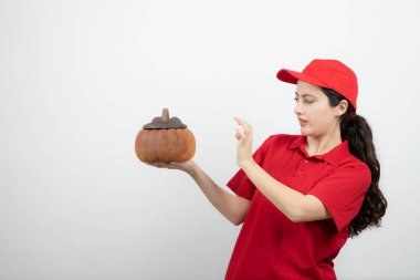 Kırmızı üniformalı esmer bir kadının elinde balkabağı resmi. Yüksek kalite fotoğraf