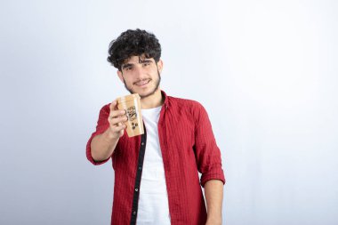Beyaz duvarda mola vermek için elinde kahve tutan esmer adamın fotoğrafı. Yüksek kalite fotoğraf