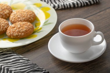 Tahta bir masaya yerleştirilmiş beyaz fincanlı çok tahıllı kurabiyeler. Yüksek kalite fotoğraf