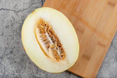 Tahta kesme tahtasına yarım dilimlenmiş sarı kavun yerleştirilmiş. Yüksek kalite fotoğraf