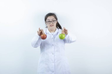 Doktor üniformalı genç bir kız elinde yeşil ve kırmızı elma meyveleri tutuyor. Yüksek kalite fotoğraf
