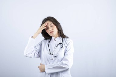 Young female doctor with stethoscope having headache on white background. High quality photo